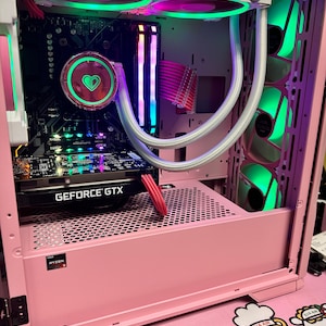 May include: A pink computer case with a clear window showing the inside. The case has a green and purple LED light strip and a graphics card with the text "GEFORCE GTX" on it. The case also has a pink and white CPU cooler with a green LED light.