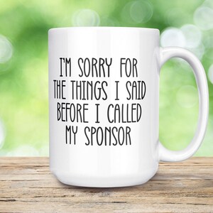 May include: White ceramic coffee mug with black text that reads "I'm sorry for the things I said before I called my sponsor".