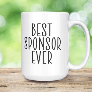 May include: White ceramic coffee mug with black text that reads "Best Sponsor Ever".