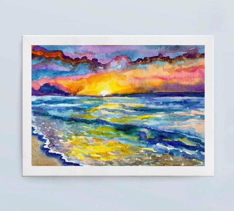 Op de afbeelding: Waterverf schilderij van een zonsondergang boven de oceaan. De lucht is een mix van paars, roze en oranje, met wolken die de kleuren reflecteren. De oceaan is diepblauw, met golven die breken op de kust. Het schilderij is ingelijst in een wit frame.