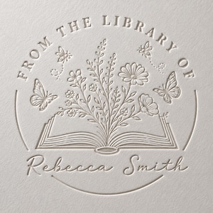 May include: An embossed circular stamp design on textured paper featuring an open book with a bouquet of wildflowers emerging from the pages. The text reads FROM THE LIBRARY OF and Rebecca Smith, accompanied by two butterflies and two bees.