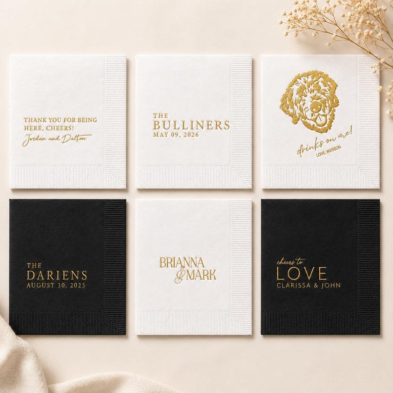 May include: Six square paper napkins in white and black with gold foil text and graphics. Designs include names, dates, and phrases like 'Thank you for being here, cheers!', 'The Bulliners', 'Drinks on me!', 'The Dariens', 'Brianna & Mark', and 'Cheers to love'.