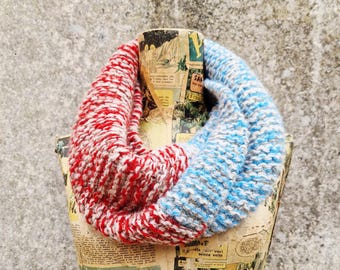 May include: A knitted infinity scarf in red, white, and blue yarn, displayed on a mannequin covered in vintage comic strips. The cowl is a cosy accessory for cold weather. The scarf is a blend of red and white on one side and blue and white on the other.