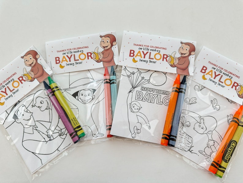 May include: Four party favor bags with coloring pages featuring Curious George and the text "Thanks for celebrating our little monkey Baylor turning three!" and "Happy Birthday Baylor". Each bag includes a set of crayons.