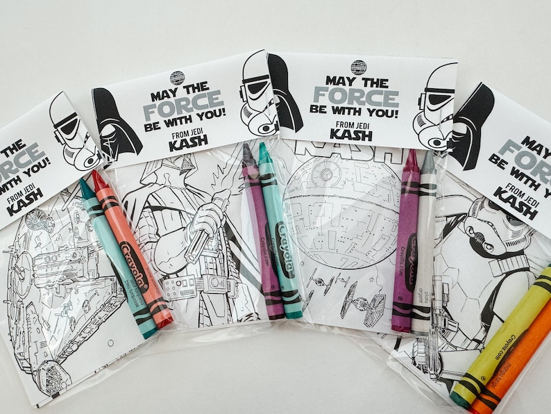 May include: Four Star Wars themed coloring pages with crayons in plastic bags. Each bag has a different character or spaceship from the Star Wars movies. The bags have a tag that says "May the Force be with you! From Jedi Kash".