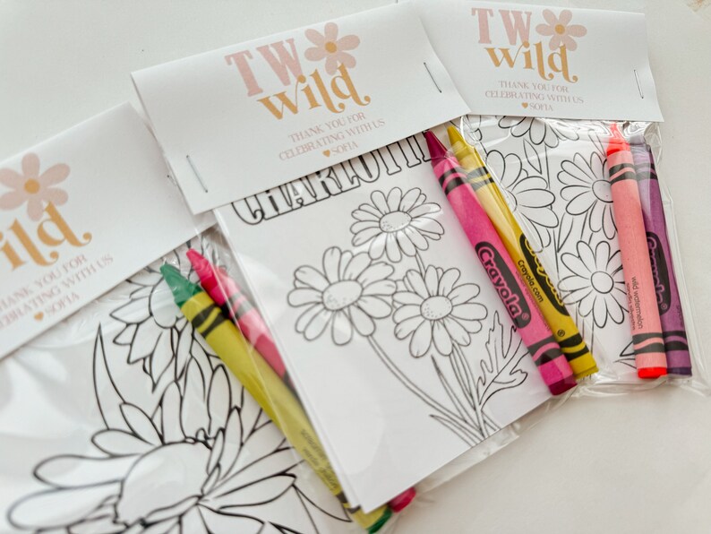 May include: A set of four favor bags with a coloring page and crayons. The bags are decorated with a pink and white floral design and the text "TW Wild" and "Thank you for celebrating with us Sofia".