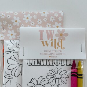 May include: A pink and white favor bag with a white card that says "Two Wild" in pink and gold letters. The card also says "Thank you for celebrating with us" and "Sofia" in pink letters. The bag contains a coloring page with a daisy design and three crayons.