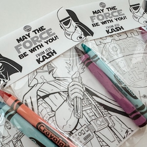 May include: A set of Star Wars themed coloring pages with crayons. The pages feature Darth Vader, a Death Star, and a Stormtrooper. The text on the pages reads "May the Force be with you! From Jedi Kash."