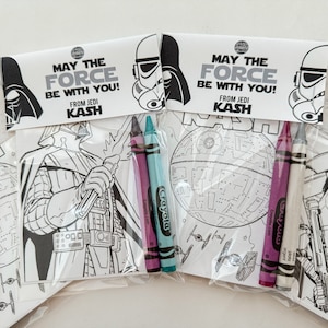 May include: Two Star Wars themed coloring pages with crayons. One page features Darth Vader and the other features the Death Star. The pages have the text "May the Force be with you! From Jedi Kash" on them.