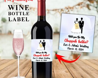 May include: A wine bottle label with a white background and a cartoon illustration of a bride and groom. The text on the label reads "Will you Be My Chuppah holder? Lori & Adam's Wedding March 15, 2024".