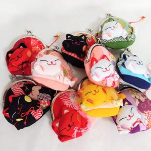 Può includere: Una collezione di portamonete con un design a forma di gatto. Le borse sono disponibili in vari colori, tra cui rosso, nero, rosa, giallo, verde e blu. Ogni borsa ha una chiusura in metallo ed è decorata con un'applicazione a forma di gatto in 3D.