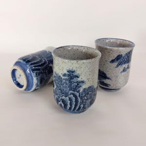 Könnte beinhalten: Drei blaue und weiße Keramik-Teetassen mit einem gesprenkelten Überzug und einem japanischen Landschaftsdesign.