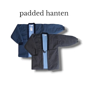 Peut inclure: Deux vestes hanten rembourrées, une bleu foncé et une gris anthracite, avec des manches longues à poignets côtelés, un col foncé et une doublure intérieure bleu clair. Le texte "padded hanten" est affiché au-dessus des deux vêtements.