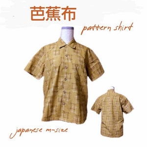 May include: A short-sleeved, button-down shirt in a mustard yellow color with a white grid pattern. The shirt is displayed on a mannequin, with a smaller version of the shirt shown below. Text on the image reads "pattern shirt" and "japanese m-size".