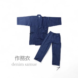 以下が含まれることがあります： 濃い青色のデニム作務衣セット。ジャケットとパンツで構成されています。ジャケットはラップスタイルで、袖が広い。パンツはウエストに紐が付いています。「作務衣」の日本語と「denim samue」の英語テキストが表示されています。