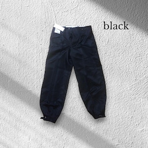 May include: Black trousers with a high waist and gathered ankles. The trousers have a button and zip fastening and a tag attached to the waistband. The word "black" is written in the upper right corner.