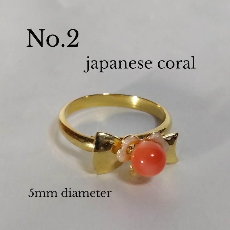 Peut inclure: Bague en or avec un n&oelig;ud et une pierre de corail japonais de 5 mm de diam&egrave;tre. La bague est &eacute;tiquet&eacute;e "No. 2 Corail japonais 5 mm de diam&egrave;tre".