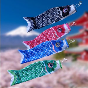 Puede incluir: Cuatro cometas con forma de pez de colores diferentes, cada uno con un patrón diferente. Las cometas son negras, rojas, azules y verdes.