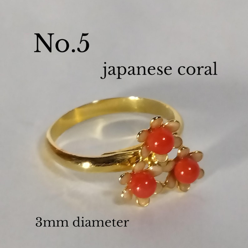 Peut inclure: Bague en or avec trois fleurs de corail rouge. Les fleurs de corail mesurent 3 mm de diam&egrave;tre. La bague est &eacute;tiquet&eacute;e "No. 5 corail japonais".