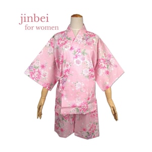May include: Pink jinbei set with a floral pattern. The set includes a kimono-style top with wide sleeves and matching shorts. The text "jinbei for women" is visible in the upper left corner. The floral design features pink and white flowers.