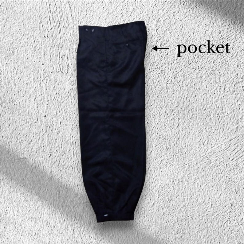 May include: A pair of navy blue trousers. The trousers have a classic design with a button and zip closure. The image shows the trousers laid flat, showcasing the pockets and overall shape.