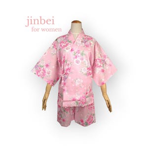 May include: Pink jinbei set for women, featuring a floral pattern of pink and white flowers. The set includes a short-sleeved top and matching shorts. The text "jinbei for women" is displayed in pink.