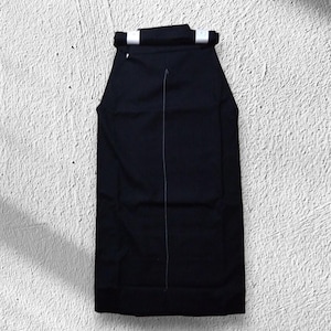 May include: A black hakama, a traditional Japanese garment, is displayed against a textured white background. The hakama features a wide, pleated design with a white seam running down the center and white accents at the top.
