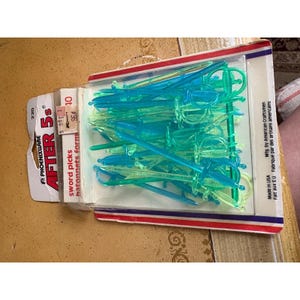 May include: A pack of blue and green plastic sword-shaped cocktail picks. The packaging includes the text "AFTER 5s" and "sword picks batonnets form". Made in the USA.