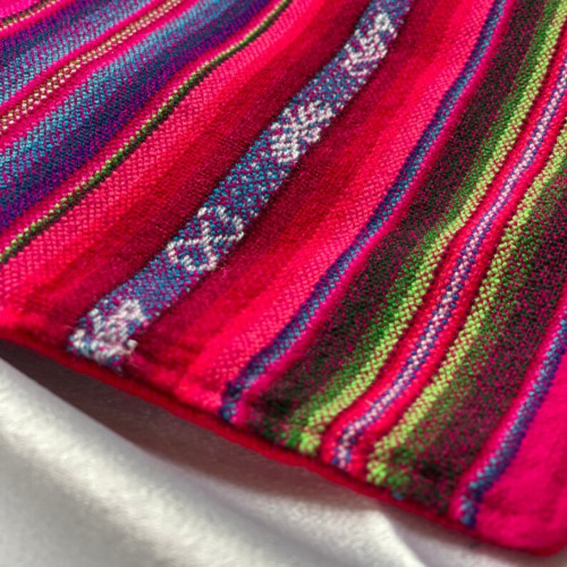 May include: Close-up of a colorful striped fabric with pink, blue, green, and white stripes. The fabric has a woven texture and is made of a soft material.