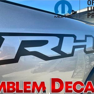 May include: Black and silver "RHO" emblem decals for a vehicle. The decals are officially licensed Mopar products.