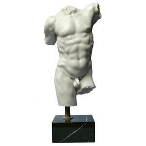 May include: White marble statue of a male torso on a black marble base. The statue is missing the head and arms.