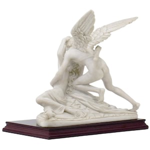 May include: A white marble sculpture of Cupid and Psyche. Cupid is depicted with wings and is holding Psyche in his arms. The sculpture is on a dark wood base.