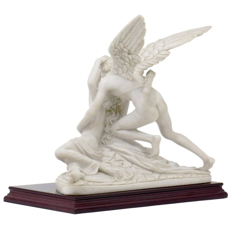 May include: A white marble sculpture of Cupid and Psyche. Cupid is depicted with wings and is holding Psyche in his arms. The sculpture is on a dark wood base.