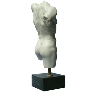May include: White marble sculpture of a male torso on a black marble base with a gold metal stand.