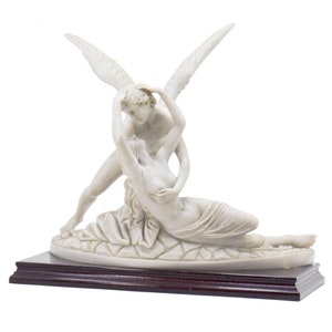 May include: A white marble sculpture of a couple embracing. The man has wings and is holding the woman in his arms. The sculpture is on a dark wood base.