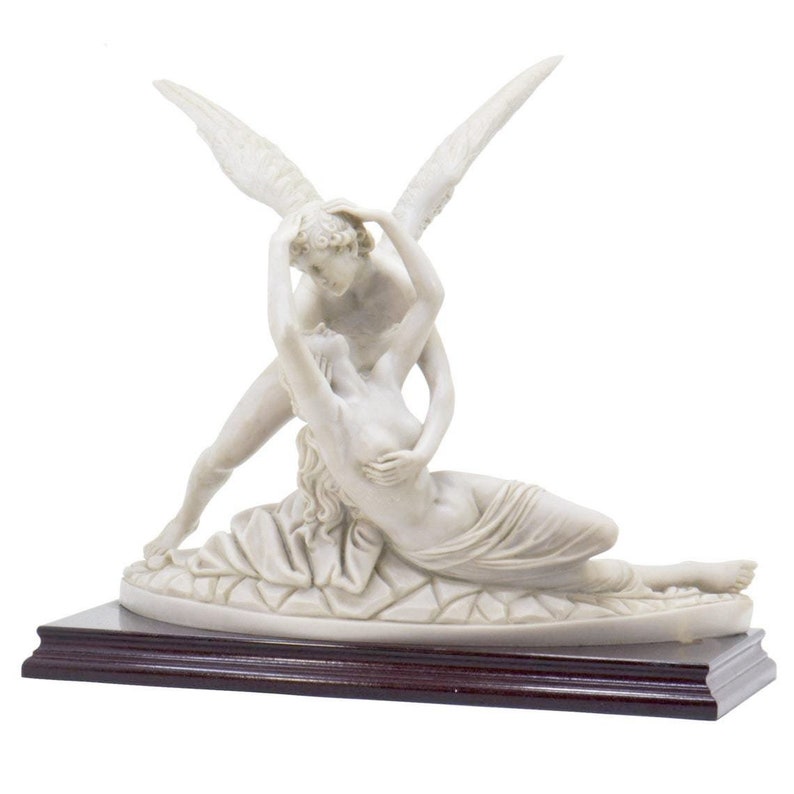 May include: A white marble sculpture of a couple embracing. The man has wings and is holding the woman in his arms. The sculpture is on a dark wood base.