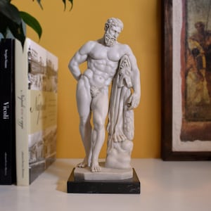 May include: White marble statue of a nude male figure standing on a black marble base. The figure is holding a drapery in his left hand and has a beard.