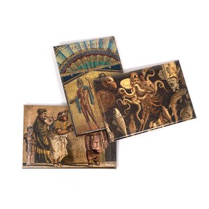 May include: Three rectangular magnets featuring images of ancient Roman mosaics. The first magnet depicts a mosaic of a man standing in a blue robe. The second magnet depicts a mosaic of an octopus with fish and other sea creatures. The third magnet depicts a mosaic of three people standing in a row.