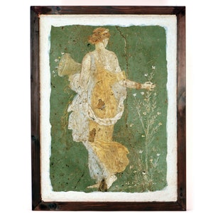 May include: A framed painting of a woman in a white and yellow dress, holding a basket of flowers. She is standing in a green field with white flowers.