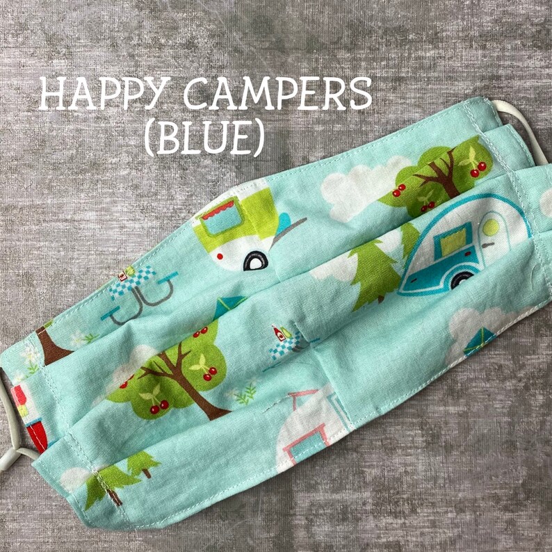 May include: A blue fabric face mask with a pattern of happy campers, trees, and cherries. The text "HAPPY CAMPERS (BLUE)" is printed on the mask.