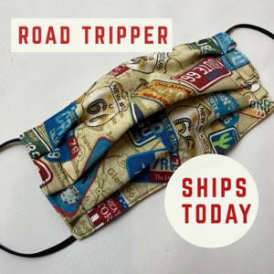 May include: A face mask with a road trip theme. The mask is made of fabric and has a variety of road signs and maps printed on it. The mask is folded and has a black elastic band.