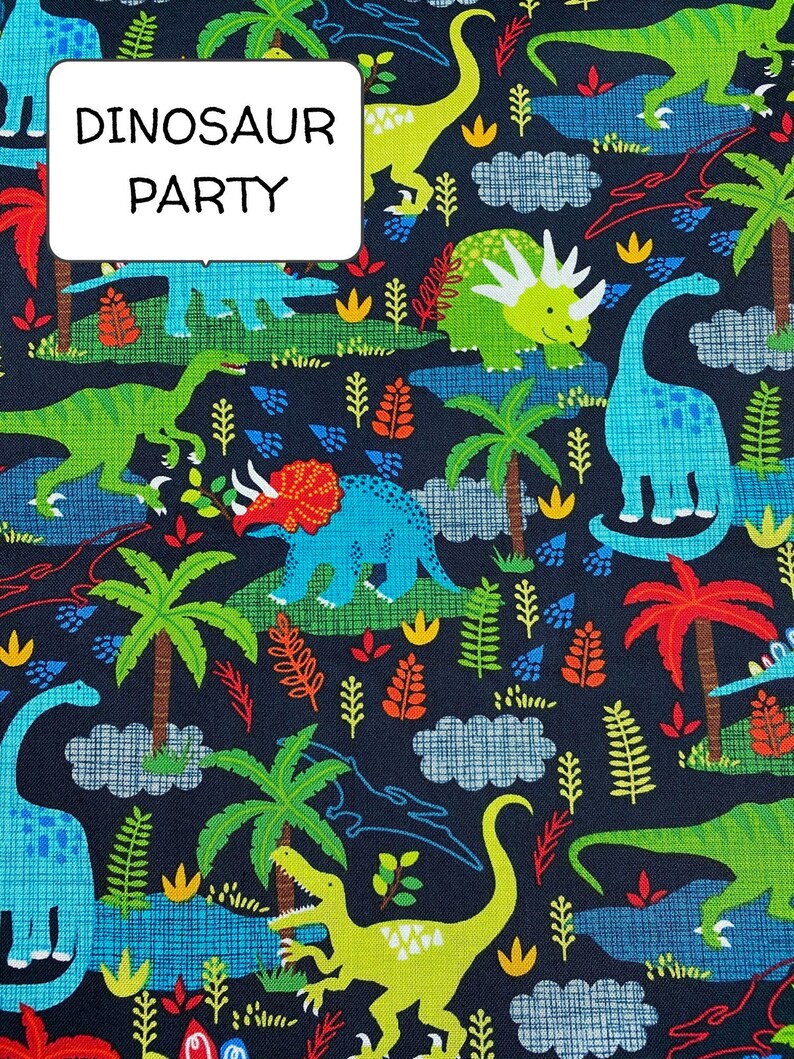 May include: A dark blue fabric with a repeating pattern of dinosaurs, palm trees, and clouds. The text "Dinosaur Party" is printed in white on a white rectangle.