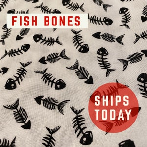 May include: White fabric with a black repeating pattern of fish bones. The text "FISH BONES" is in red at the top of the image. The text "SHIPS TODAY" is in white on a red circle at the bottom of the image.