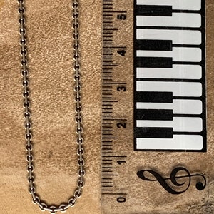 May include: A silver chain necklace measuring approximately 6 inches in length. The chain is made of small, linked circles.