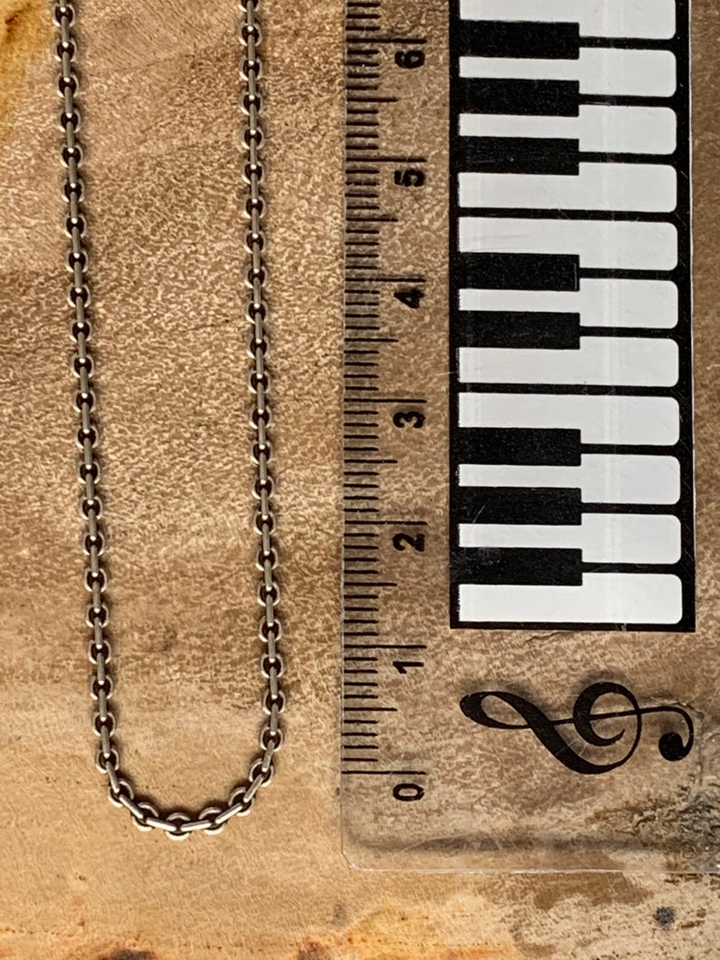 May include: A silver chain necklace measuring approximately 6 inches in length. The chain is made of small, linked circles.