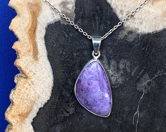 May include: A silver chain necklace with a purple and white gemstone pendant. The pendant is a teardrop shape and has a silver bail.