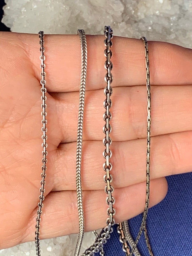 May include: Four silver chains of different styles and thicknesses.
