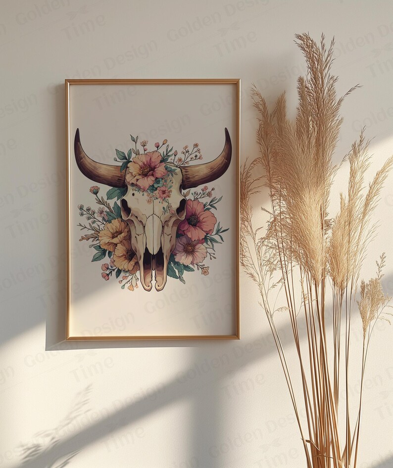 May include: A framed print of a white bull skull with pink and yellow flowers around it. The skull is surrounded by a wreath of flowers. The background is white.