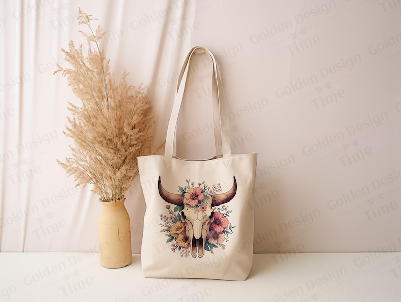 May include: A white canvas tote bag with a floral skull design. The skull is surrounded by pink, yellow, and green flowers. The bag has two handles.