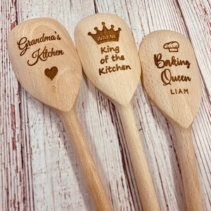 May include: Three wooden spoons with engraved text. The first spoon says "Grandma's Kitchen" with a heart. The second spoon says "Wayne King of the Kitchen" with a crown. The third spoon says "Liam Baking Queen" with a chef's hat.